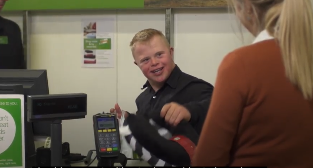 A young man with disability working as a cashier at a department store
